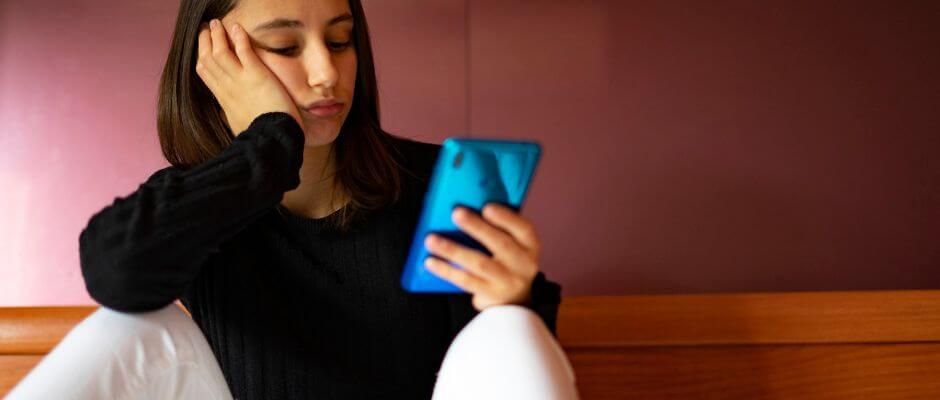 mulher entediada vendo celular